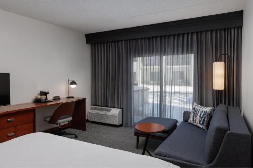 a hotel room with a bed and a couch and a window at Courtyard by Marriott Denver Central Park in Denver