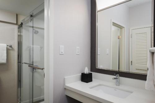 a white bathroom with a sink and a mirror at Courtyard by Marriott Denver Central Park in Denver