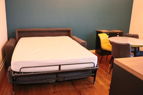 Ce lit se trouve dans un dortoir doté d'une table et de chaises. dans l'établissement Appartement 2/4 pers Vacance-Cure cosy et ensoleillé, à La Bourboule