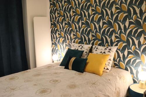 - une chambre dotée d'un lit avec des oreillers et du papier peint dans l'établissement Appartement 2/4 pers Vacance-Cure cosy et ensoleillé, à La Bourboule