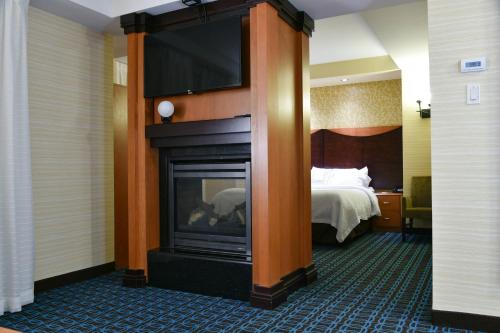 una camera d'albergo con camino e TV sopra di Fairfield Inn Hartford Airport a Windsor Locks
