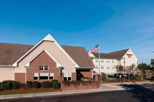 a house with an american flag in front of a building at Residence Inn by Marriott Hattiesburg in Hattiesburg