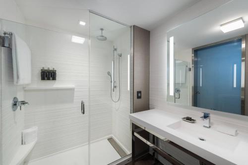 a white bathroom with a shower and a sink at AC Hotel by Marriott Worcester in Worcester