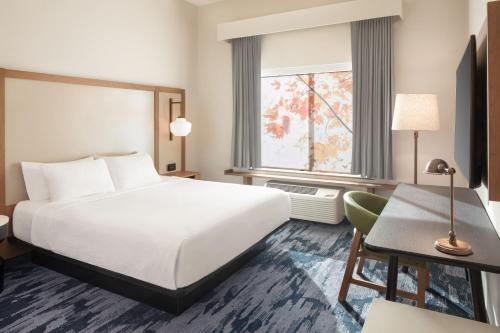 a hotel room with a bed and a desk and a window at Fairfield Inn & Suites by Marriott Fresno North/Shaw Avenue in Fresno