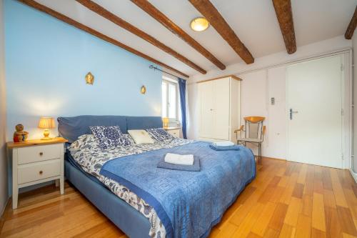 a bedroom with a blue bed and a wooden floor at Apartment Buena Vista Piran in Piran