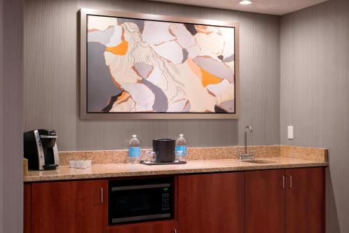 a kitchen with a microwave and a sink with a picture on the wall at Courtyard by Marriott Denver Airport in Denver