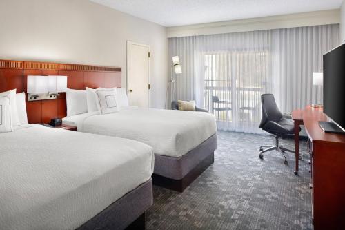 a hotel room with two beds and a desk at Courtyard by Marriott Perimeter Center in Atlanta