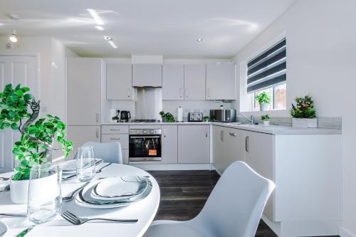 a white kitchen with a table and white chairs at Videl Homes in Manchester