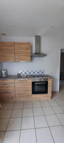 une cuisine avec des armoires en bois et un four à plaques de cuisson dans l'établissement Gîte à la ferme le vivier, à Lottinghen