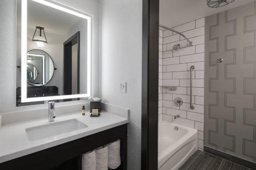 a bathroom with a sink and a tub and a mirror at The Notary Hotel, Philadelphia, Autograph Collection in Philadelphia