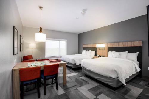 TownePlace Suites by Marriott Houston Hobby Airport في هيوستن: غرفة فندقية بسريرين وطاولة وكراسي