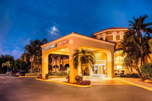 a hotel with palm trees in a parking lot at Courtyard by Marriott Fort Lauderdale North/Cypress Creek in Fort Lauderdale