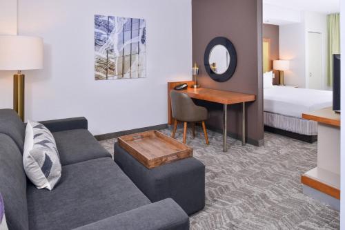 una sala de estar con sofá y escritorio en una habitación de hotel en SpringHill Suites Fairfax Fair Oaks, en Fairfax