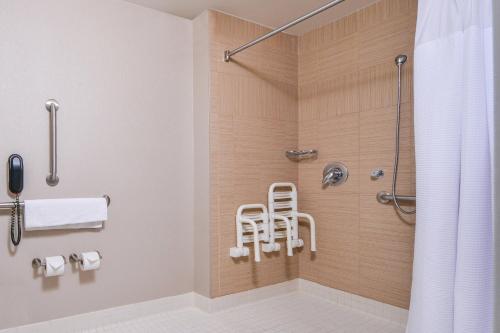 La salle de bains est pourvue d'une douche et d'une chaise. dans l'établissement SpringHill Suites Fairfax Fair Oaks, à Fairfax