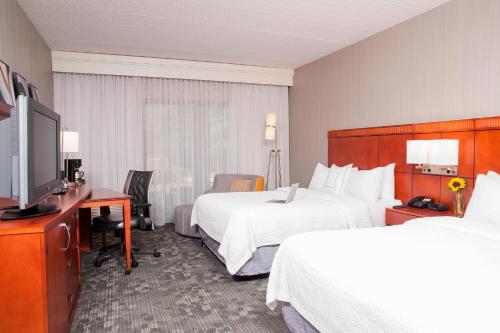 a hotel room with two beds and a flat screen tv at Courtyard Chicago Glenview/Northbrook in Glenview