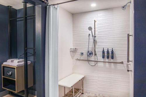 baño con cabina de ducha y taburete en Aloft Framingham, en Framingham