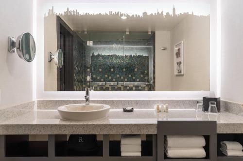 a bathroom with a sink and a large mirror at Renaissance New York Times Square Hotel by Marriott in New York