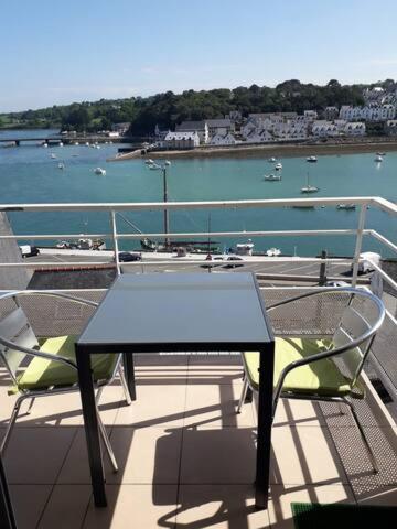 einen Tisch und Stühle auf einem Balkon mit Blick auf das Wasser in der Unterkunft appartement entier, 3 étoiles, 4 personnes,vue mer in Audierne