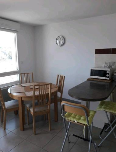 a dining room with a table and chairs and a laptop at appartement entier, 3 étoiles, 4 personnes,vue mer in Audierne