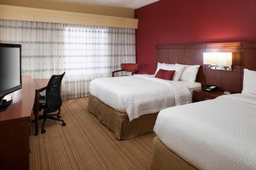 a hotel room with two beds and a desk at Courtyard by Marriott Jackson Ridgeland in Jackson