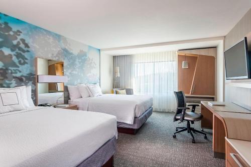 a hotel room with two beds and a desk at Courtyard by Marriott Stafford Quantico in Triangle
