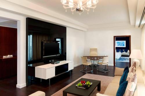 uma sala de estar com um sofá e uma televisão em Le Meridien Al Khobar em Al Khobar