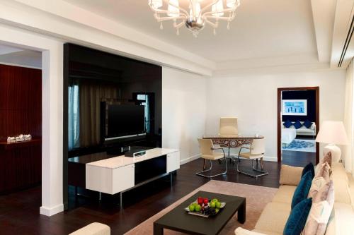 a living room with a couch and a tv at Le Meridien Al Khobar in Al Khobar