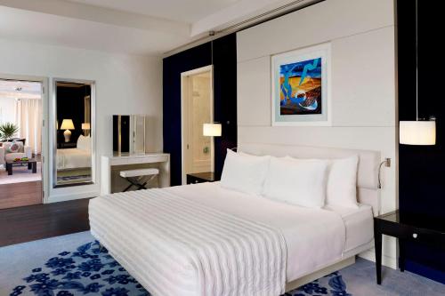 a bedroom with a large white bed and a living room at Le Meridien Al Khobar in Al Khobar