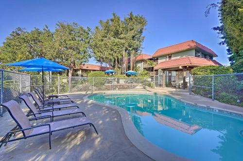 a pool with chairs and umbrellas next to a house at Less Than 1 Mi to Beach and Town! Airy Kailua-Kona Condo in Kailua-Kona
