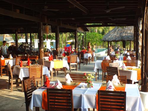 a restaurant with tables and chairs and people in the background at C&N Kho Khao Beach Resort - SHA Plus in Ko Kho Khao