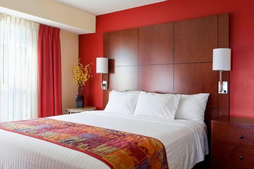 a hotel room with a large bed and red walls at Residence Inn by Marriott Peoria in Peoria