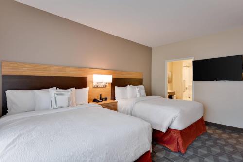 a hotel room with two beds and a flat screen tv at TownePlace Suites by Marriott Detroit Allen Park in Allen Park