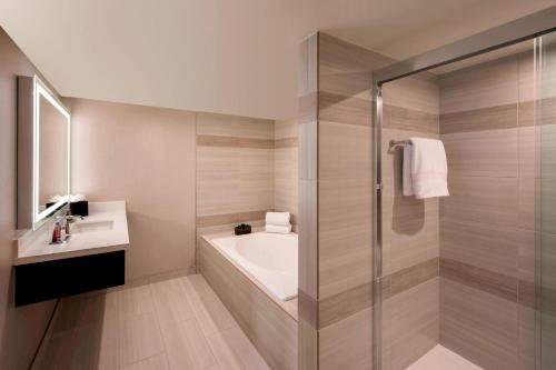 a bathroom with a shower and a tub and a sink at Denver Marriott Tech Center in Greenwood Village