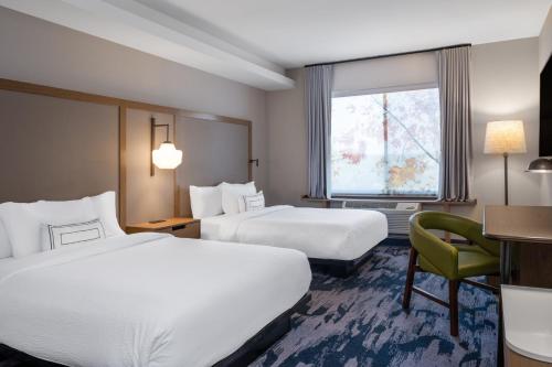 a hotel room with two beds and a chair at Fairfield Inn & Suites Minneapolis North in Brooklyn Center