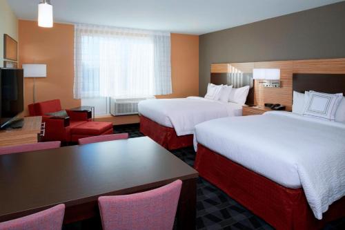 TownePlace Suites by Marriott Grand Rapids Airport في غراند رابيدز: غرفة فندقية بسريرين وطاولة وكراسي