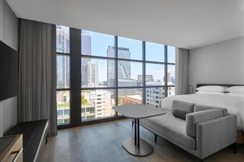 a bedroom with a bed and a couch and a large window at Courtyard by Marriott Melbourne Flagstaff Gardens in Melbourne