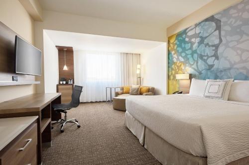エルモシージョにあるCourtyard by Marriott Hermosilloの大きなベッドとデスクが備わるホテルルームです。