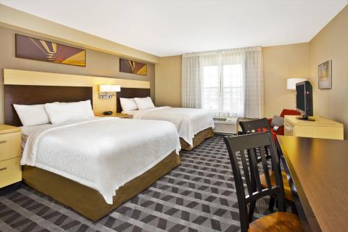 a hotel room with two beds and a desk at TownePlace Suites Republic Airport Long Island Farmingdale in Farmingdale