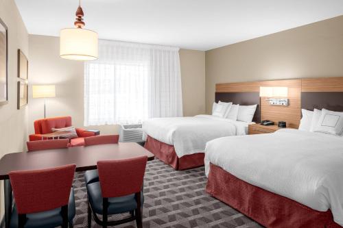 ein Hotelzimmer mit 2 Betten, einem Tisch und Stühlen in der Unterkunft TownePlace Suites Cincinnati Fairfield in Fairfield