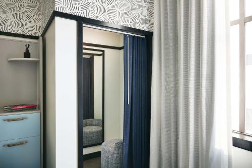uno specchio in una stanza con tenda di Kinley Cincinnati Downtown, a Tribute Portfolio Hotel a Cincinnati