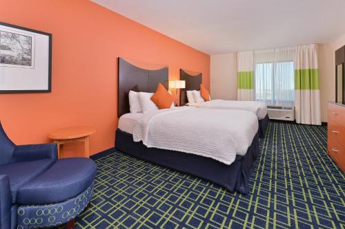 a hotel room with two beds and a chair at Fairfield Inn & Suites by Marriott Denver Aurora/Parker in Aurora