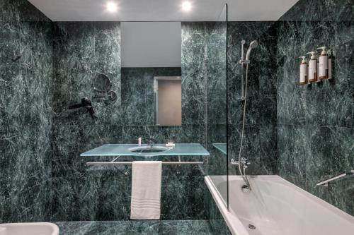 a bathroom with a sink and a tub and a shower at AC Hotel Sevilla Fórum by Marriott in Seville