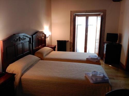 two beds in a hotel room with a window at PR San Nicolás in Santiago de Compostela