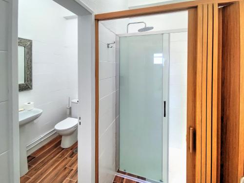 e bagno con servizi igienici e porta doccia in vetro. di Blue Ocean Guesthouse ad Atouguia da Baleia