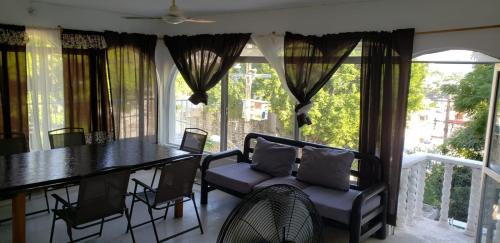 a dining room with a table and chairs and windows at Casa Costa Brava in Acapulco