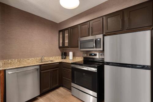 a kitchen with stainless steel appliances and brown cabinets at Residence Inn Atlanta Duluth Gwinnett Place in Duluth