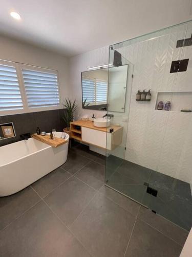 a bathroom with a tub and a sink and a shower at Yellow Door Villa in Barwon Heads