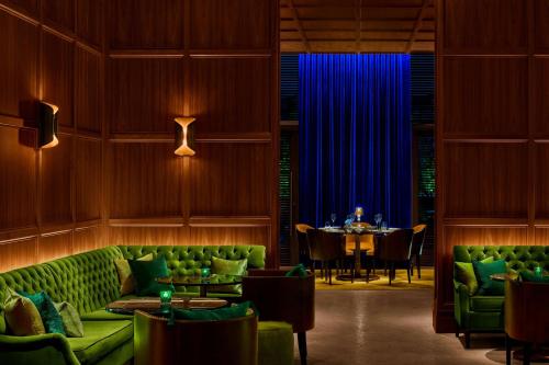 a dining room with green couches and a table at The Times Square EDITION New York in New York