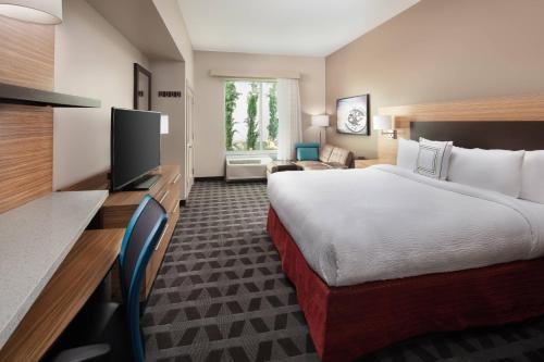 TownePlace Suites by Marriott San Diego Downtown في سان دييغو: غرفة فندقية بسرير وتلفزيون بشاشة مسطحة