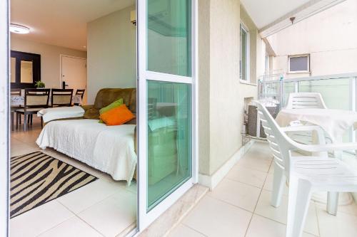een woonkamer met een bed en een glazen deur bij Confortável apto 2Qtos c/ Varanda e Vista Mar in Rio de Janeiro